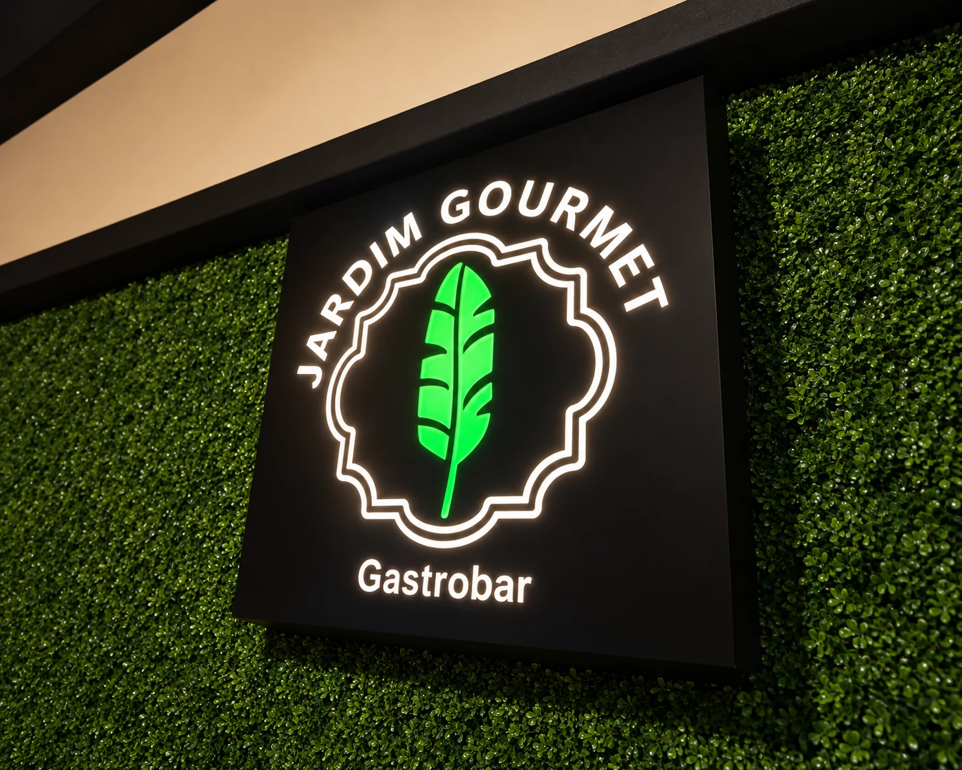 Letreiro iluminado Jardim Gourmet Gastrobar sobre parede verde